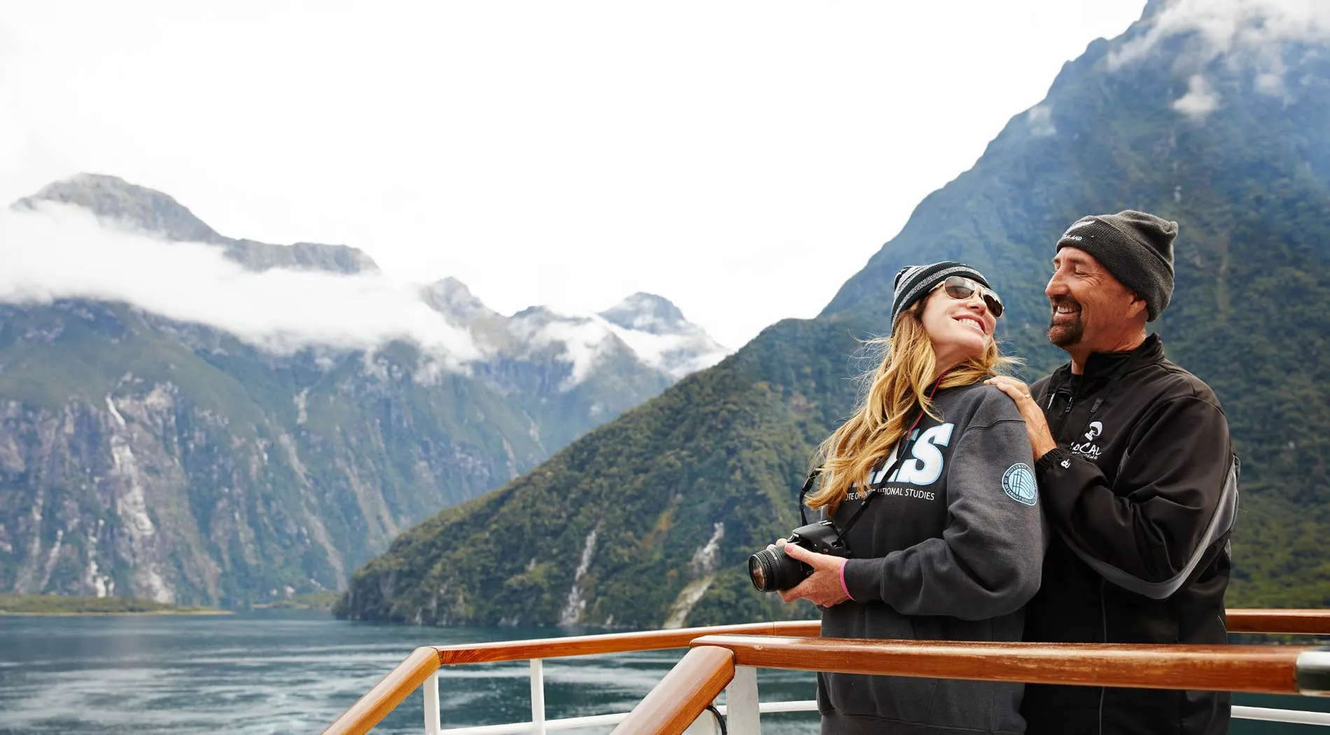Couple enjoying scenic boat tour at Milford Sound, New Zealand mountains