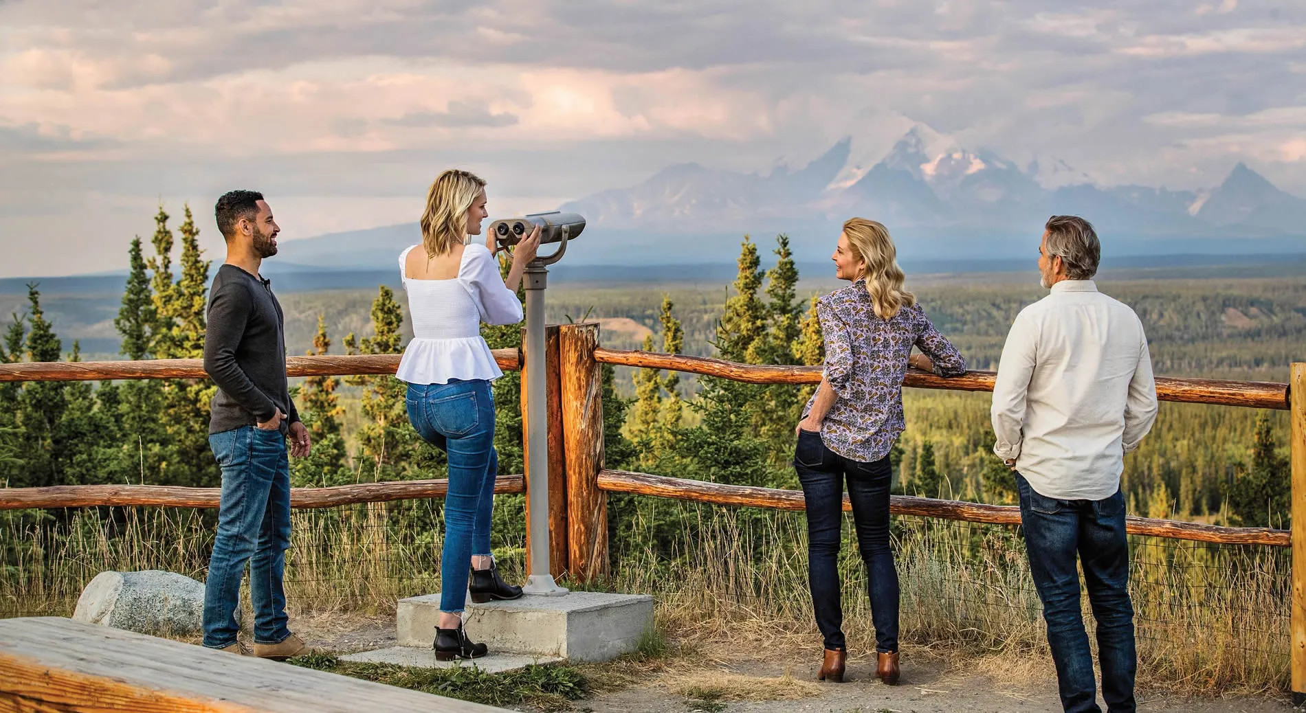 People enjoying mountain vista through binoculars at scenic overlook