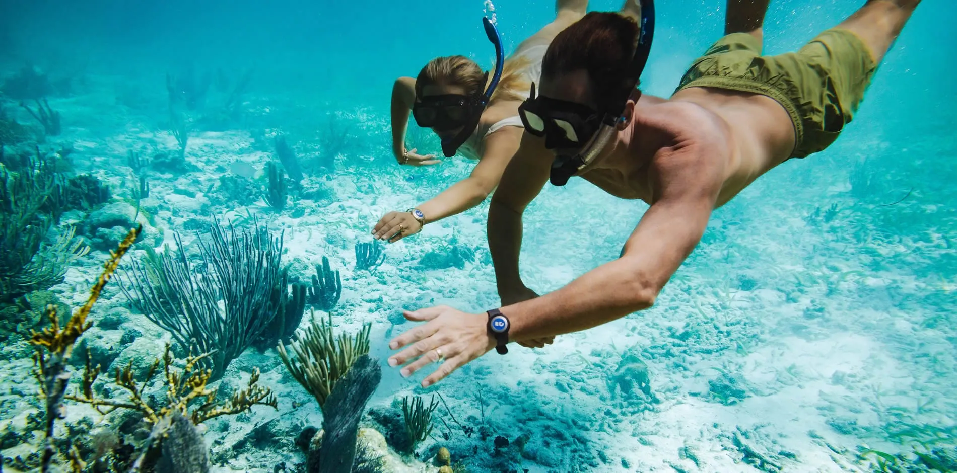 Two snorkelers exploring vibrant underwater coral reef in turquoise water