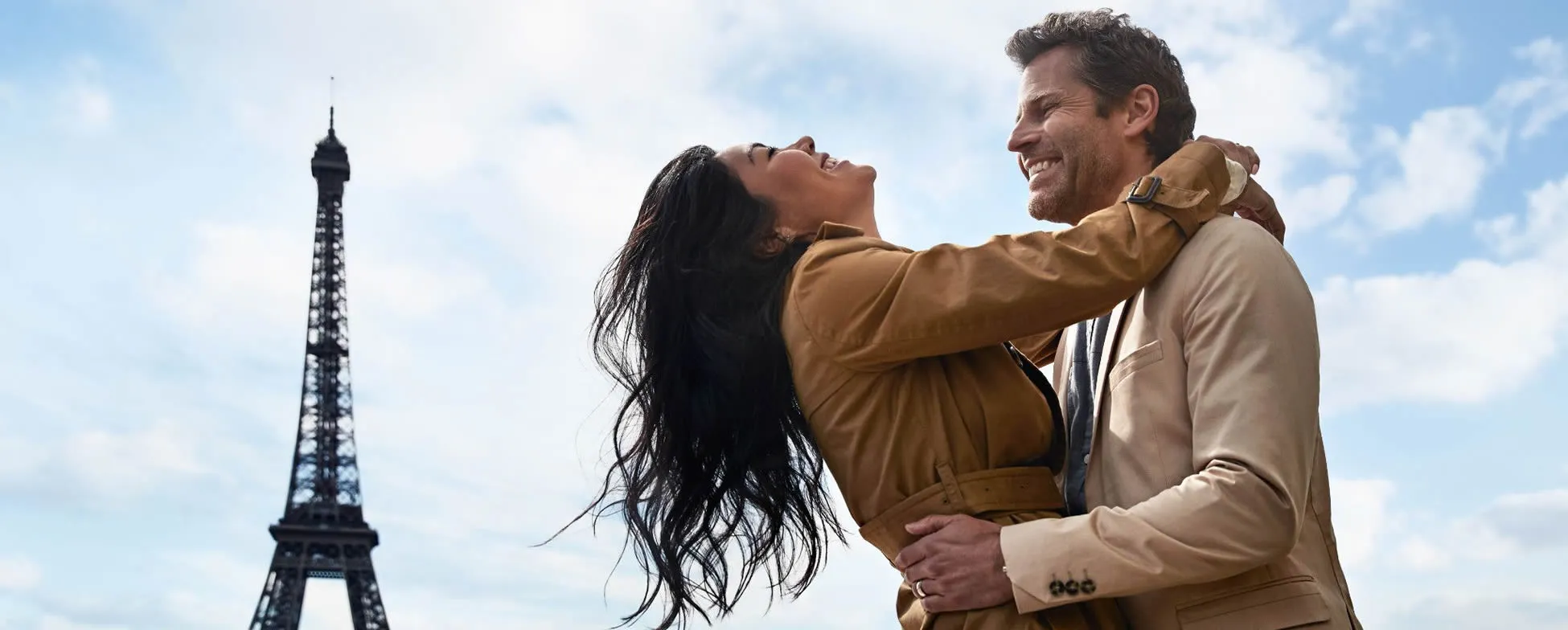 Romantic couple embracing near Eiffel Tower in Paris with blue sky