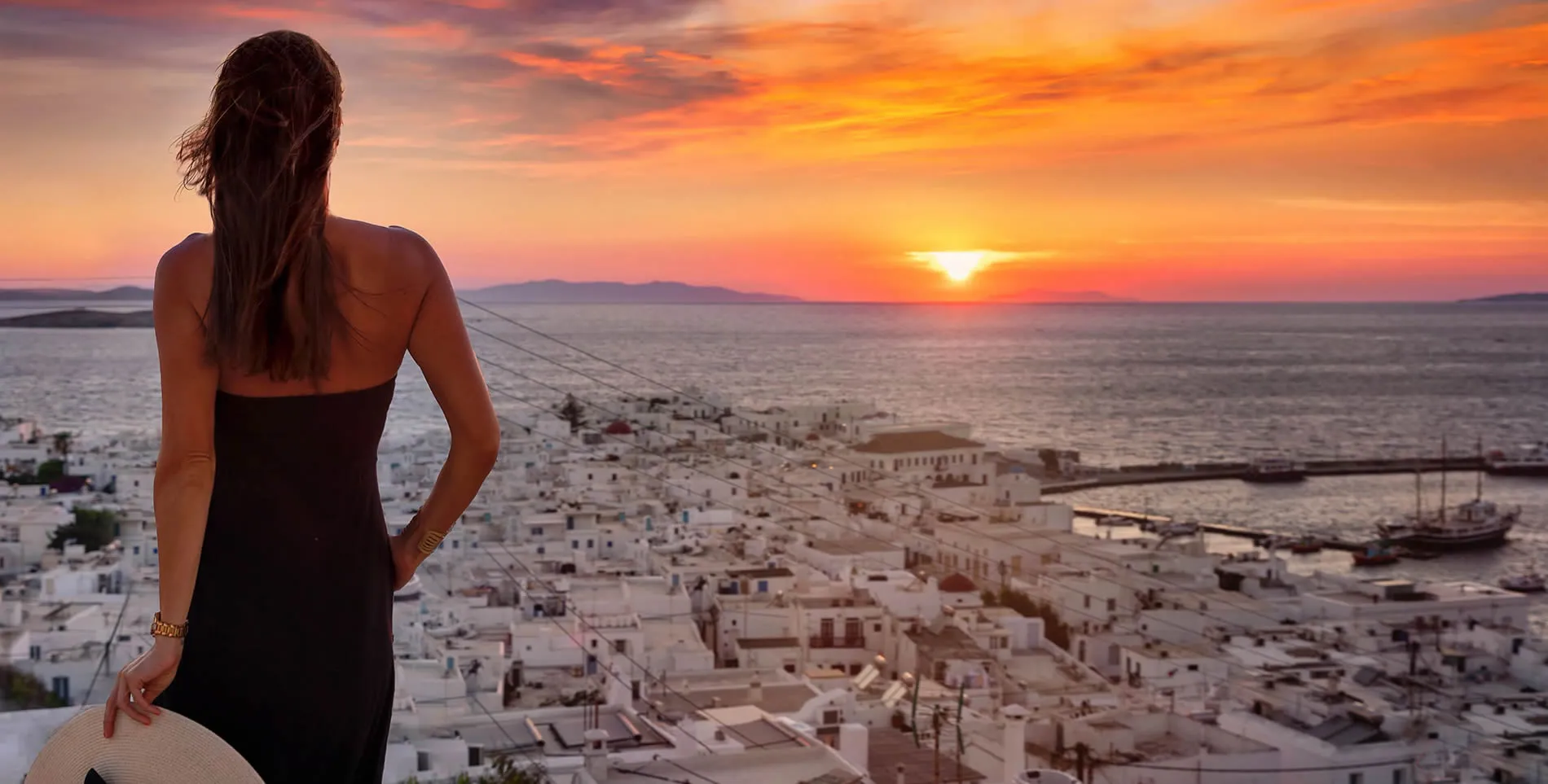 Sunset over white buildings of Mykonos with figure overlooking scenic vista
