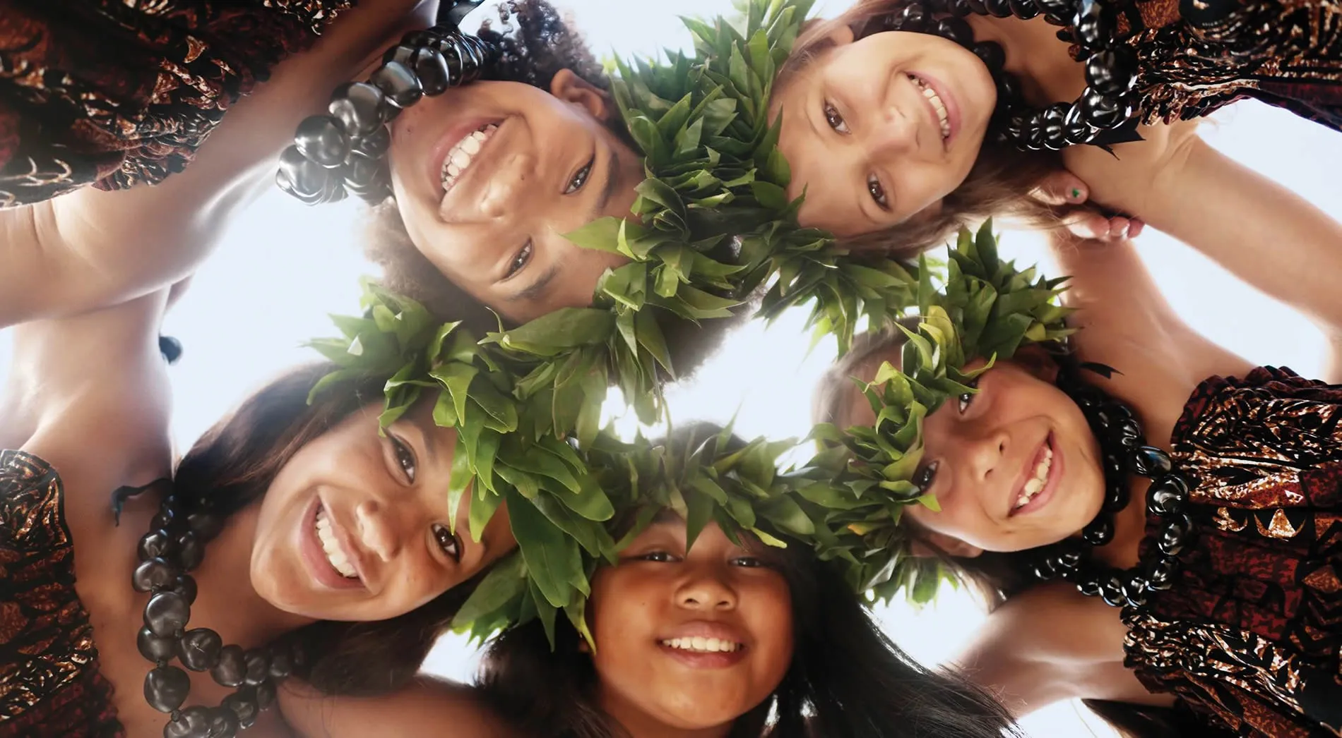 Smiling group of people with green leaf wreaths, viewed from below