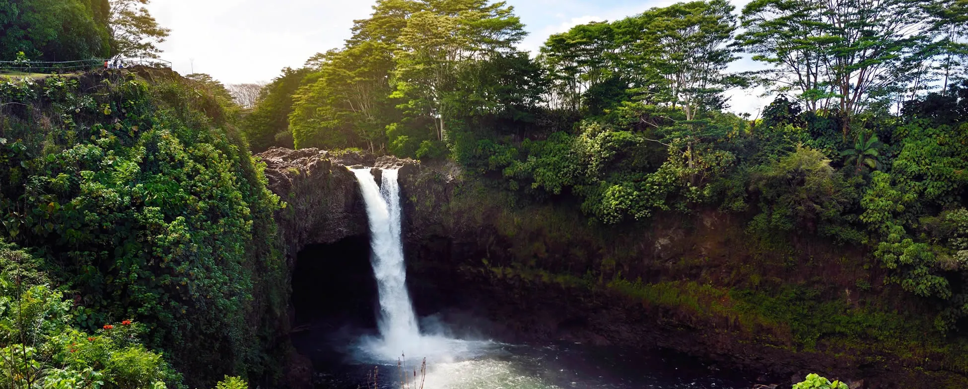 Tropical waterfall cascading through lush green forest and rocky cliffs