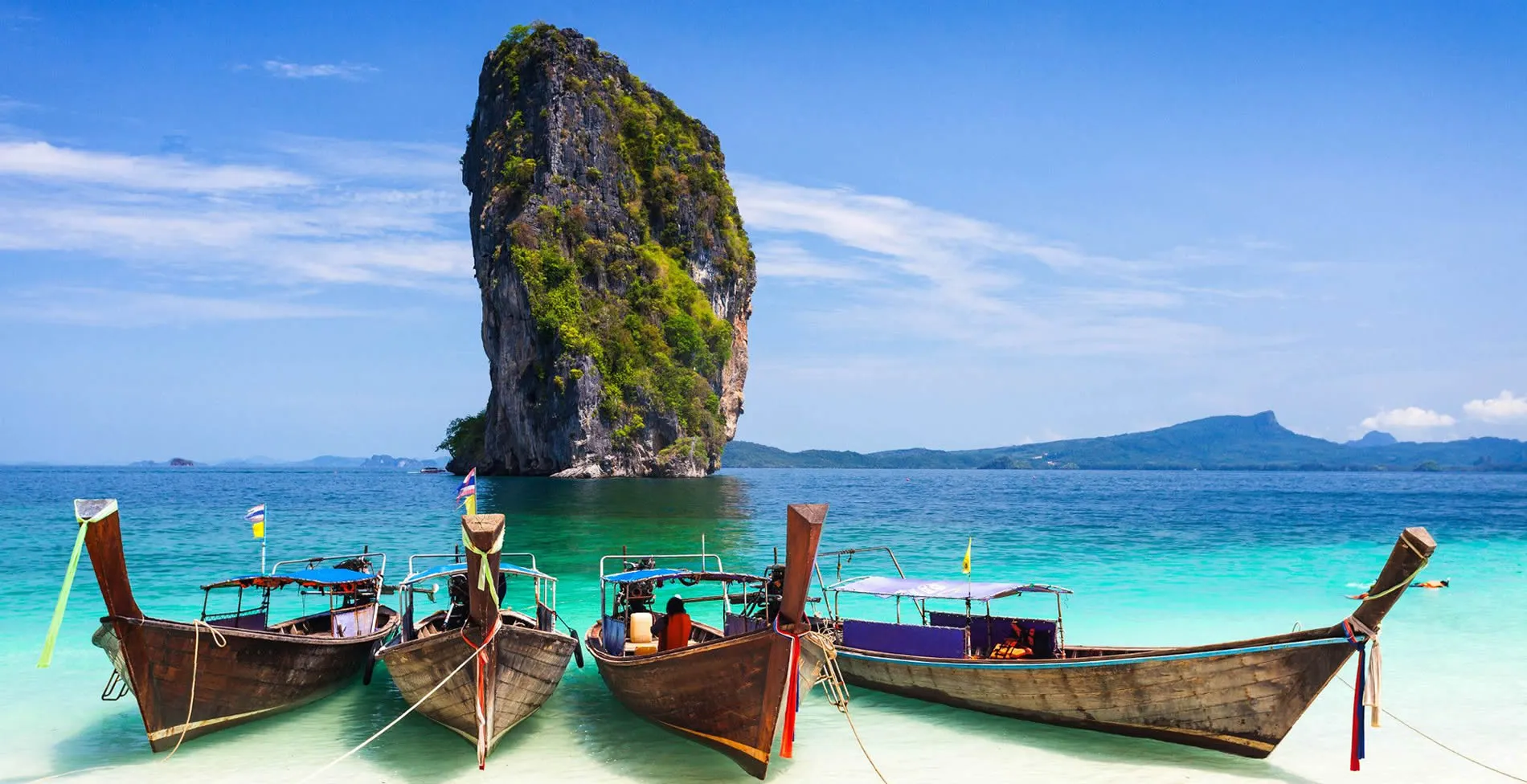 Traditional Thai long-tail boats near iconic limestone rock in Krabi