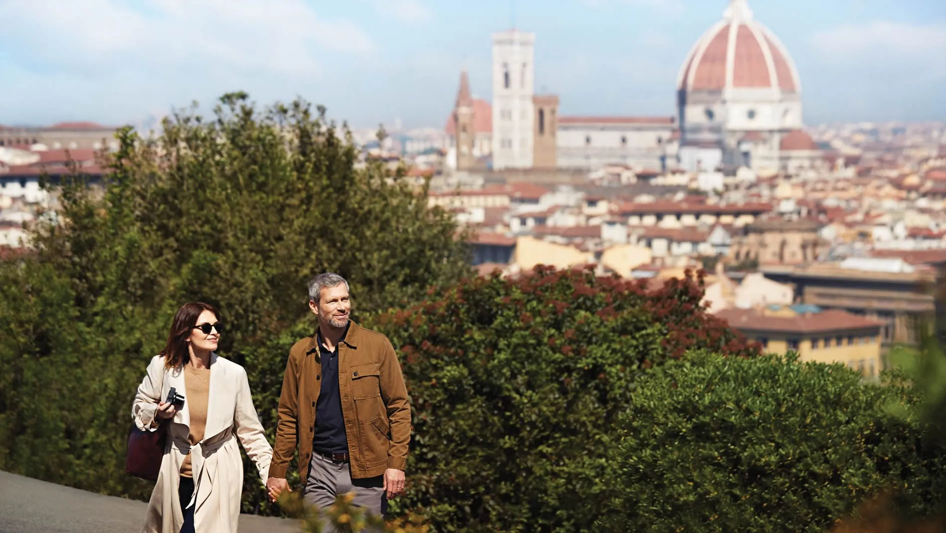 Two people walking with Florence cathedral and cityscape in background