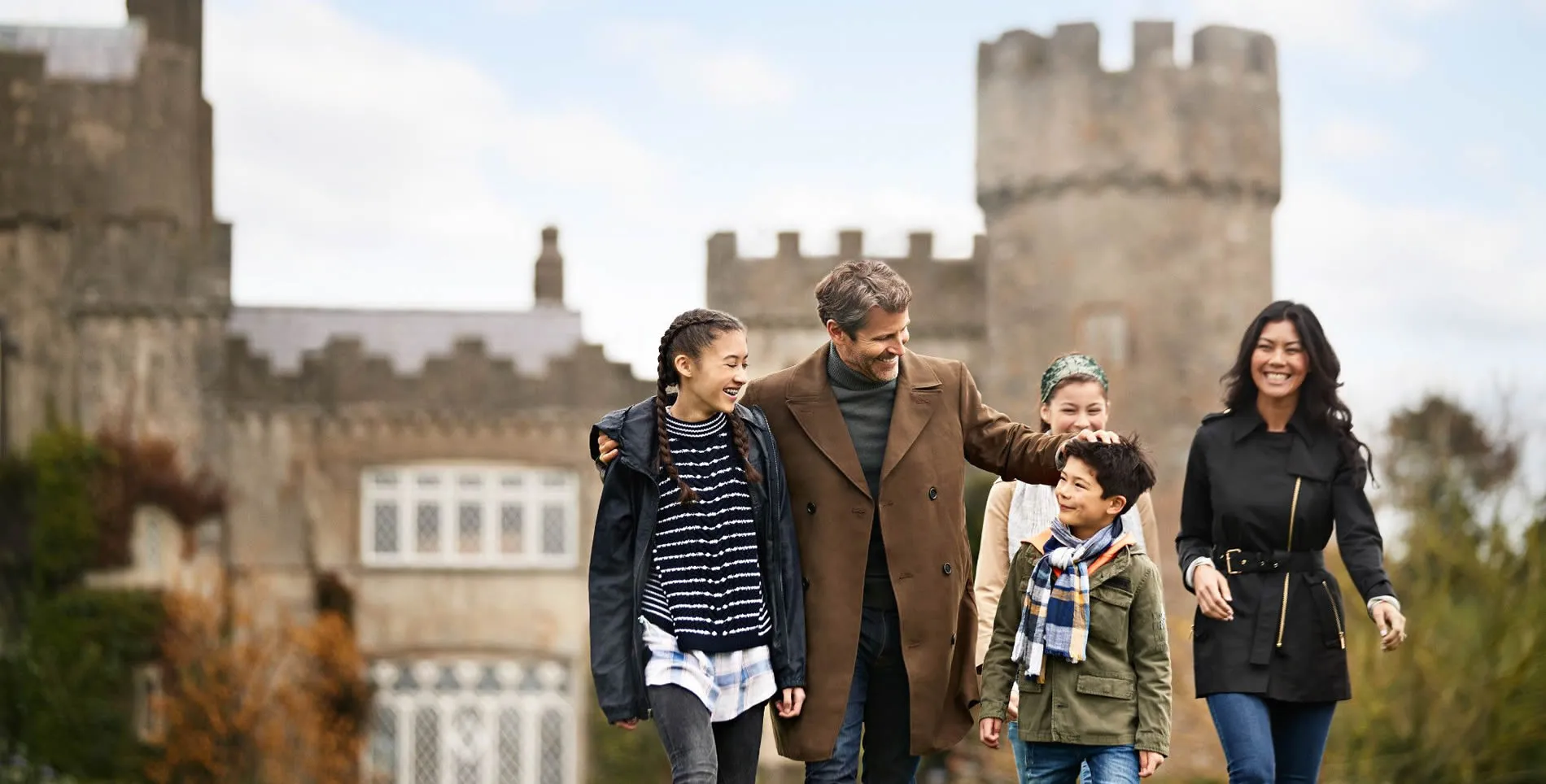 Family walking together near medieval castle on a crisp autumn day