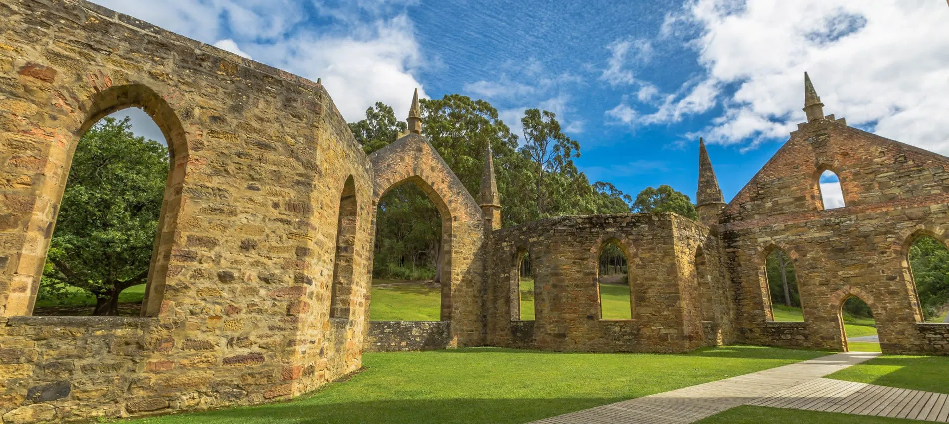 Historic stone ruins with arched windows and spires in green landscape