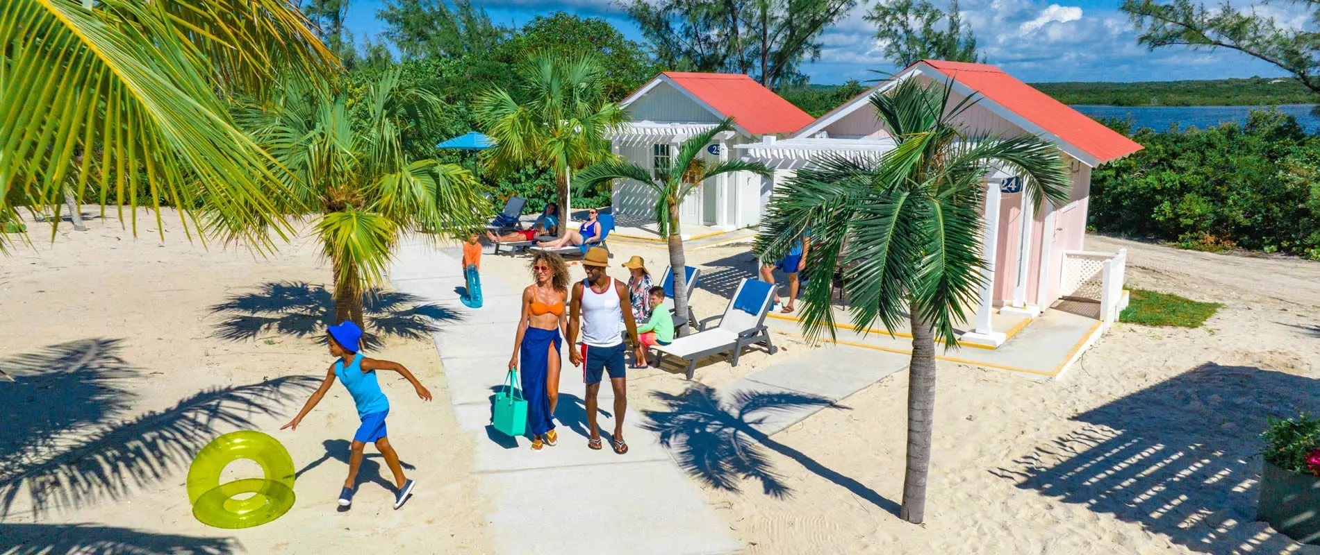 Tropical beach scene with palm trees, beach cabanas, and people enjoying vacation