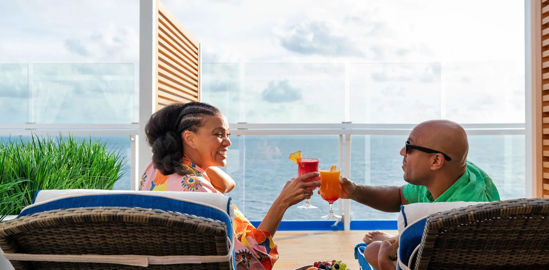 Couple toasting tropical drinks on cruise ship balcony with ocean view