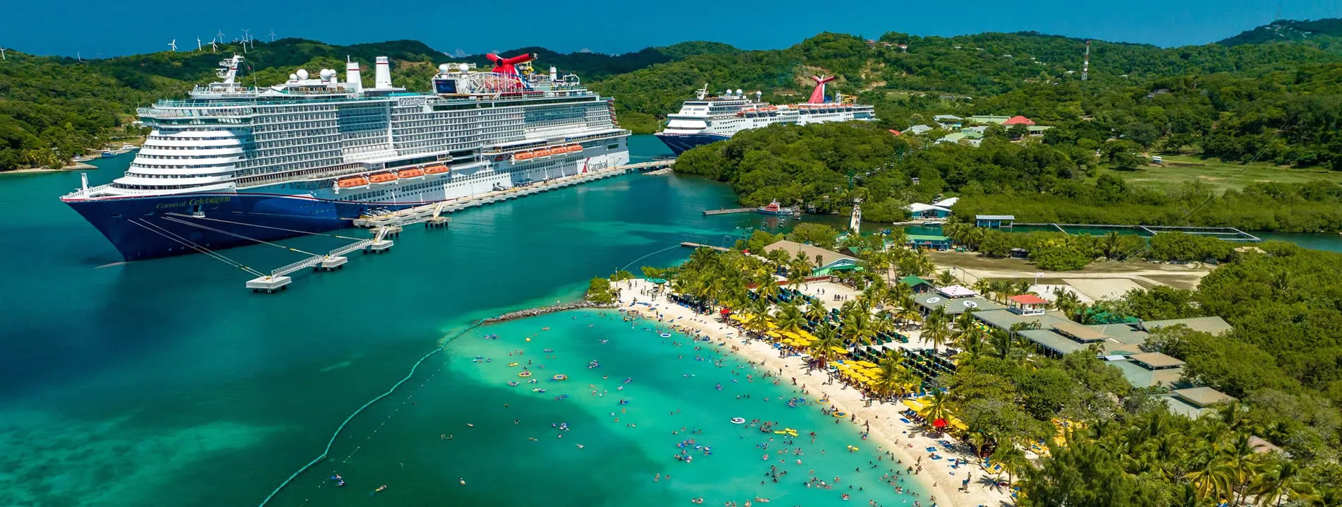 Large cruise ships docked at tropical beach with turquoise water and palm trees