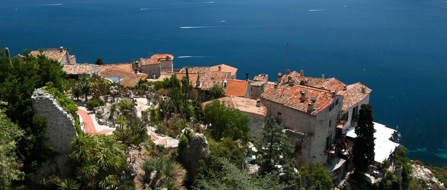 Coastal village with terracotta roofs perched on rocky cliffs overlooking blue sea