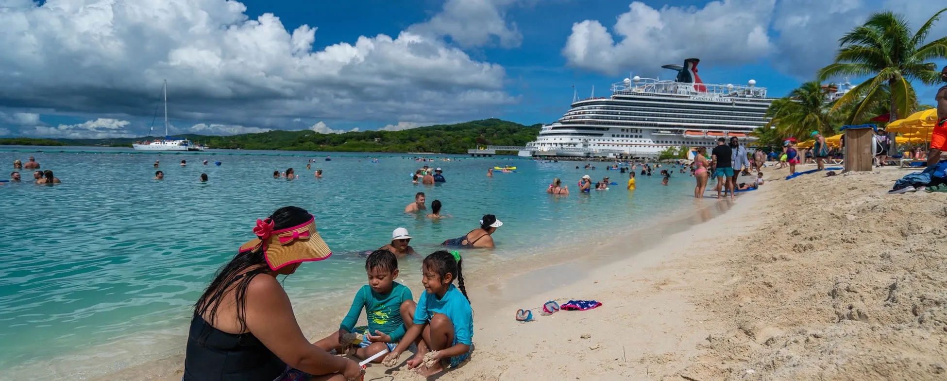 Cruise ship and families enjoying turquoise waters at tropical beach