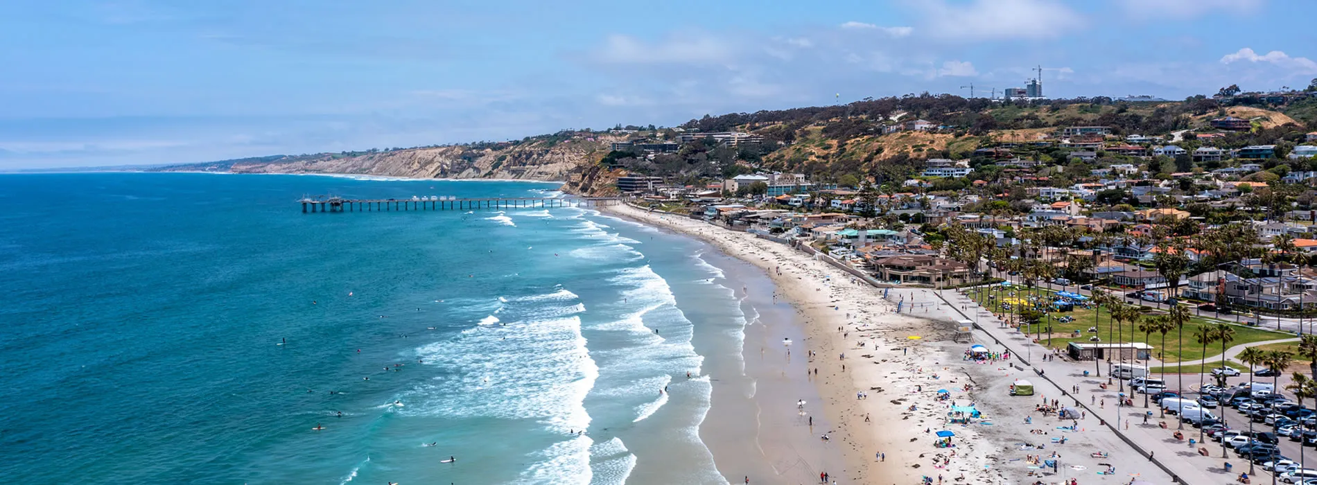 Aerial view of La Jolla Shores beach with pier, waves, and coastal buildings