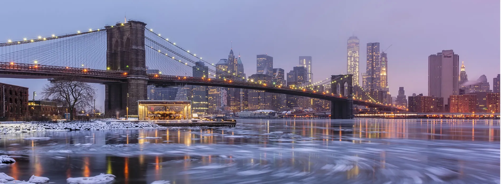 Brooklyn Bridge and Manhattan skyline at twilight with frozen East River