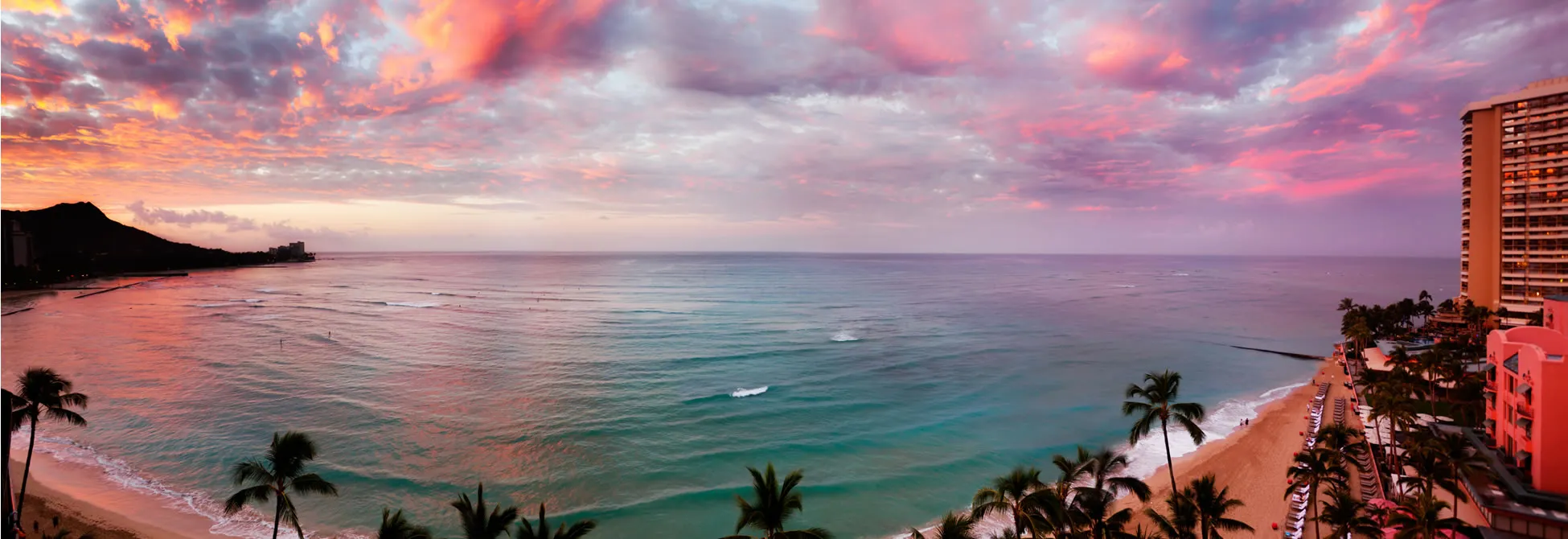 Vibrant sunset over Waikiki Beach with palm trees and ocean waves