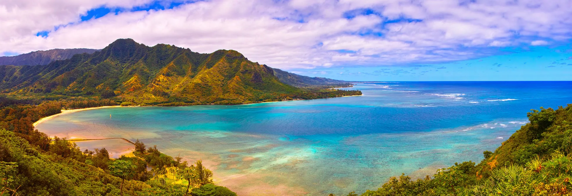 Tropical Hawaiian coastline with lush mountains and turquoise ocean waters