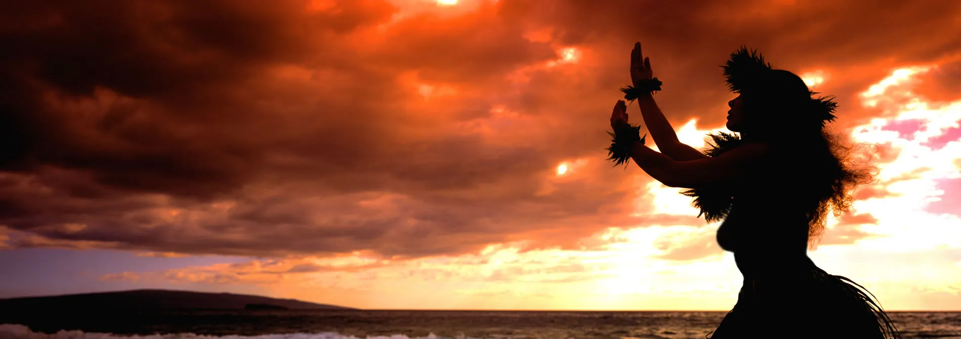 Silhouette of hula dancer at sunset with dramatic orange sky