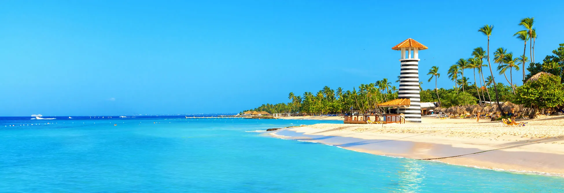 Tropical beach with striped lighthouse, palm trees, and turquoise waters