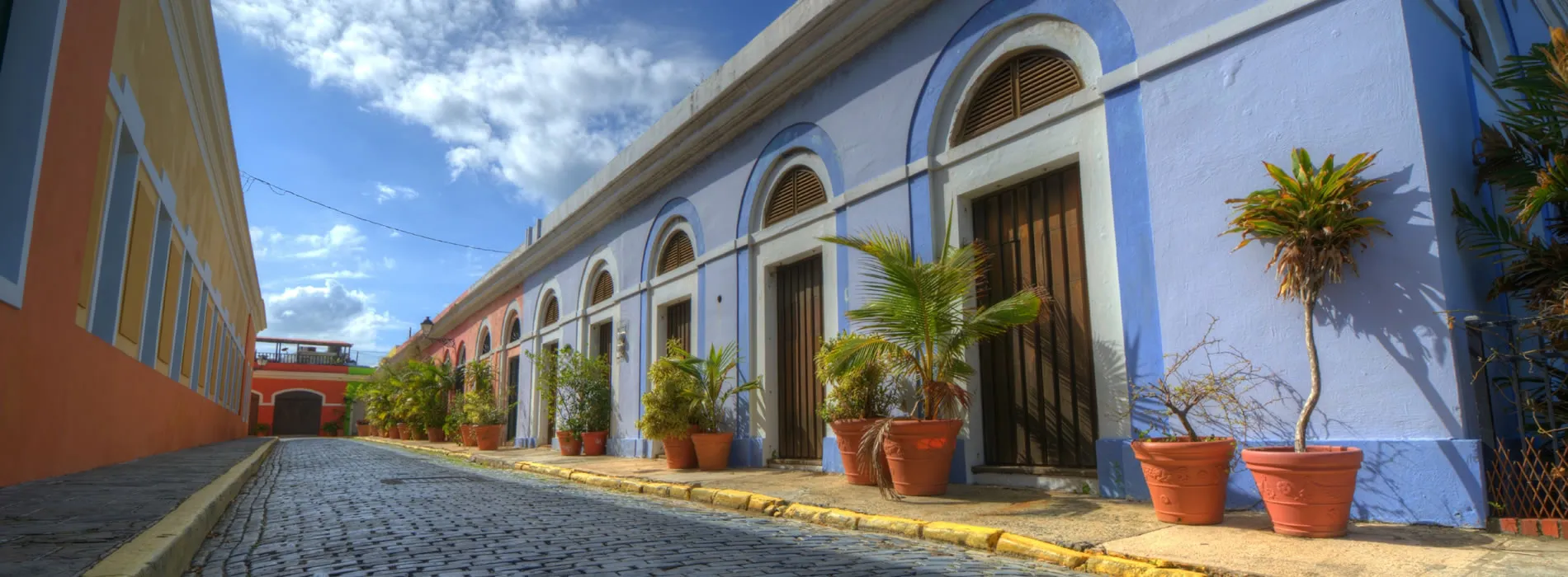 Colorful colonial street with blue buildings and potted plants in Puerto Rico