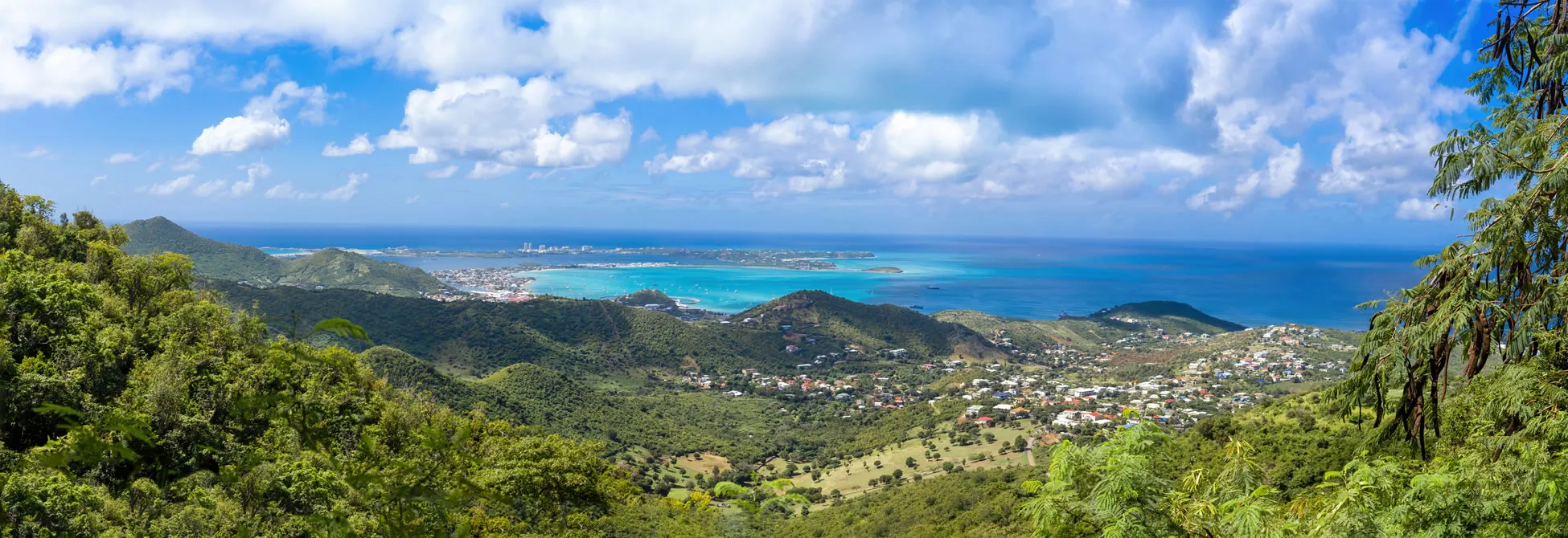 Panoramic view of green hills, town, and turquoise ocean in Saint Martin