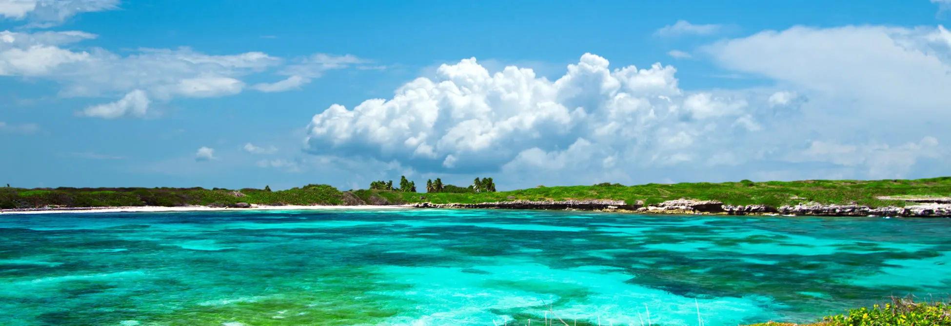 Turquoise Caribbean waters, white sandy beach, and lush green tropical landscape