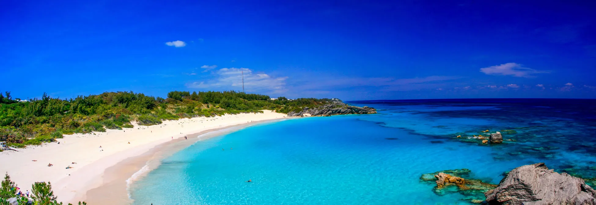 Turquoise waters and white sandy beach in Bermuda with rocky coastline
