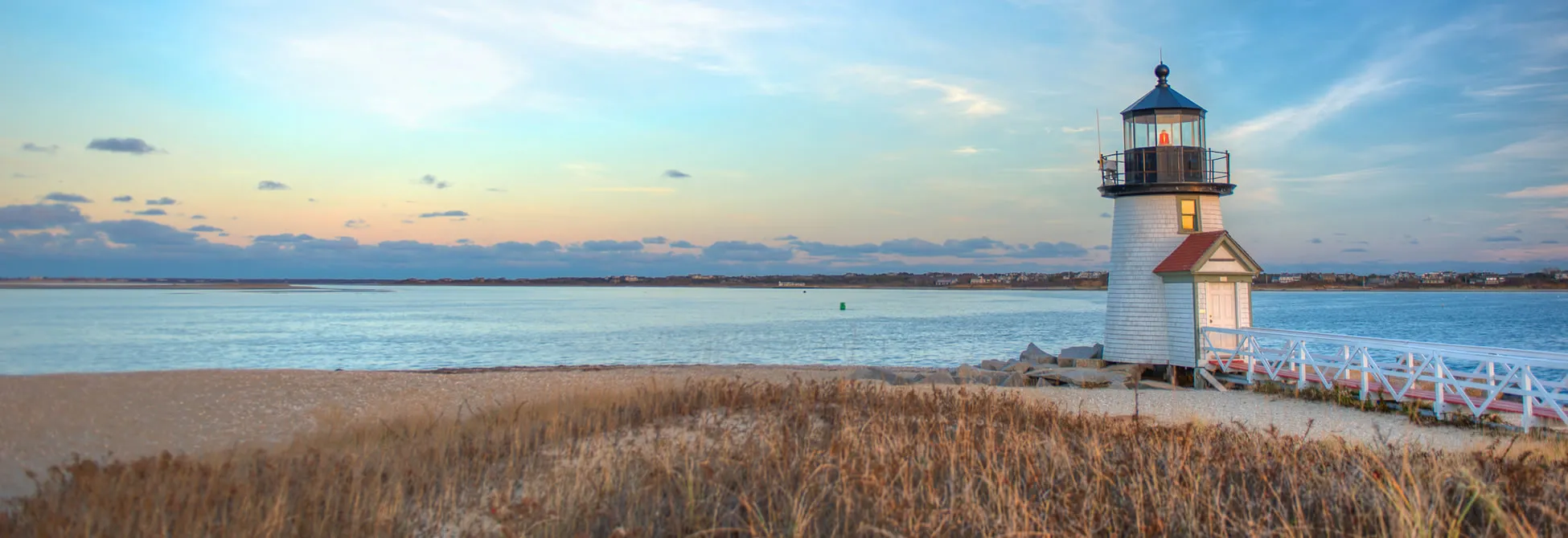 Brant Point Lighthouse at sunset on Nantucket, with calm waters and beach grass