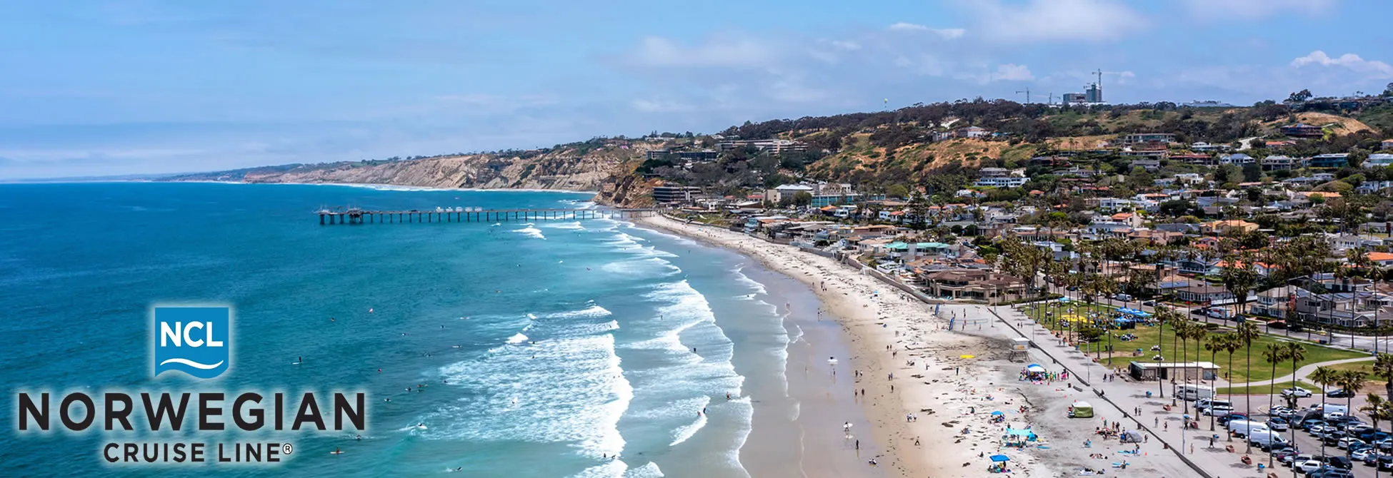Scenic La Jolla beach with pier, coastal homes, and turquoise ocean waves