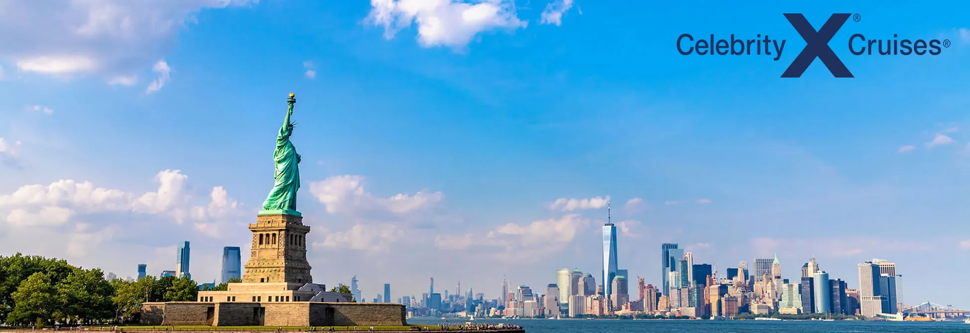Statue of Liberty with New York City skyline under bright blue sky