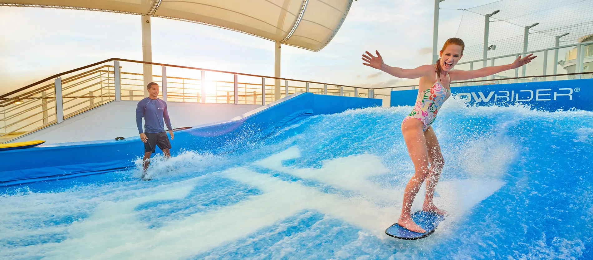 Two people surfing on artificial wave simulator on cruise ship deck