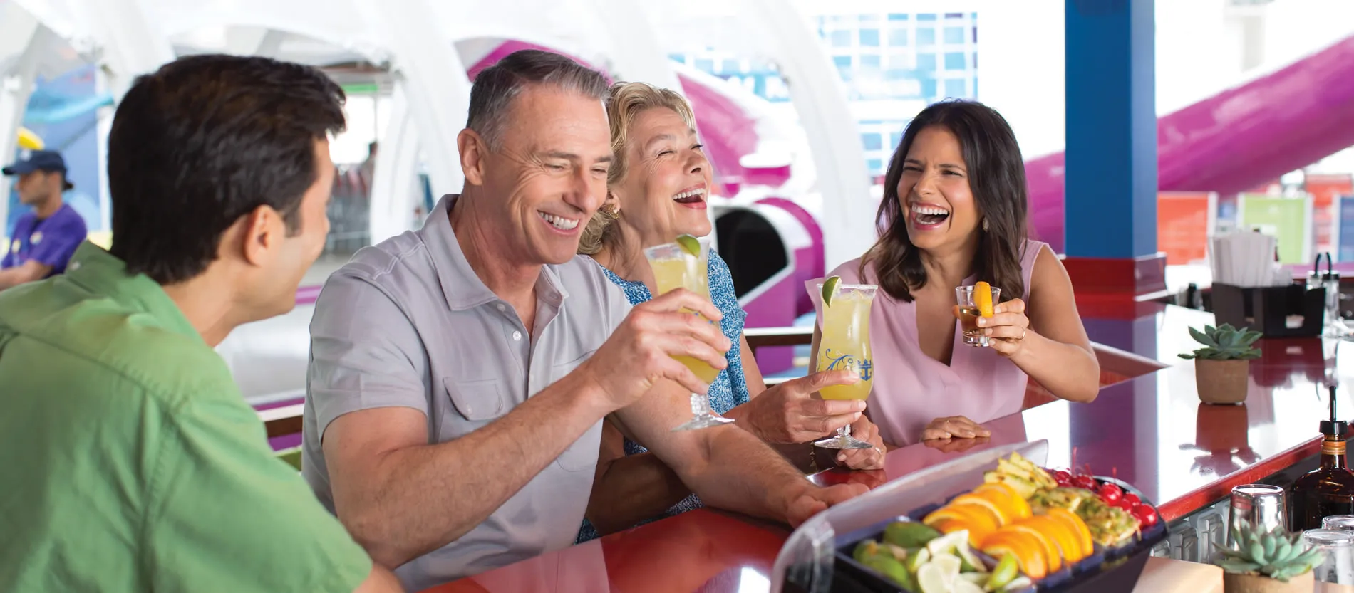 Friends laughing and enjoying cocktails at a colorful bar