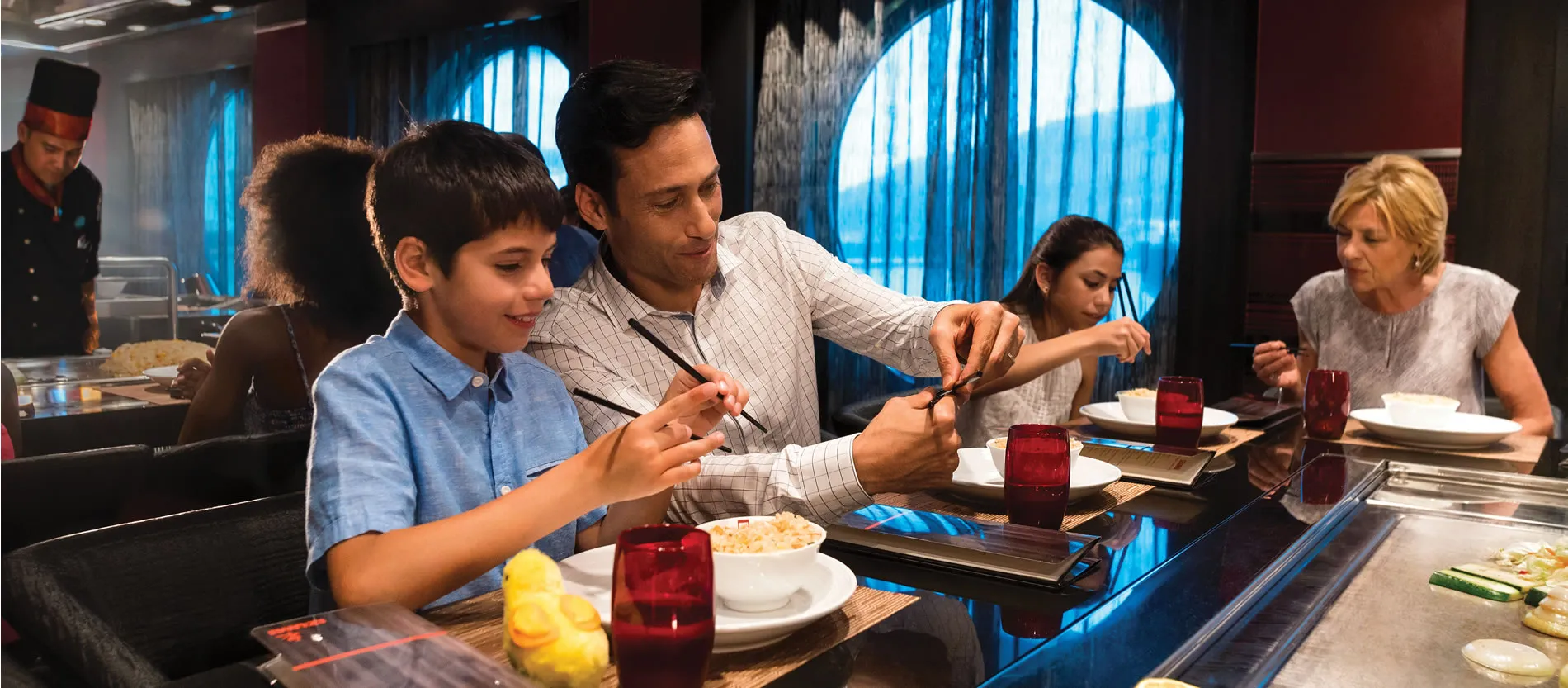 Father and son enjoying teppanyaki meal together at restaurant