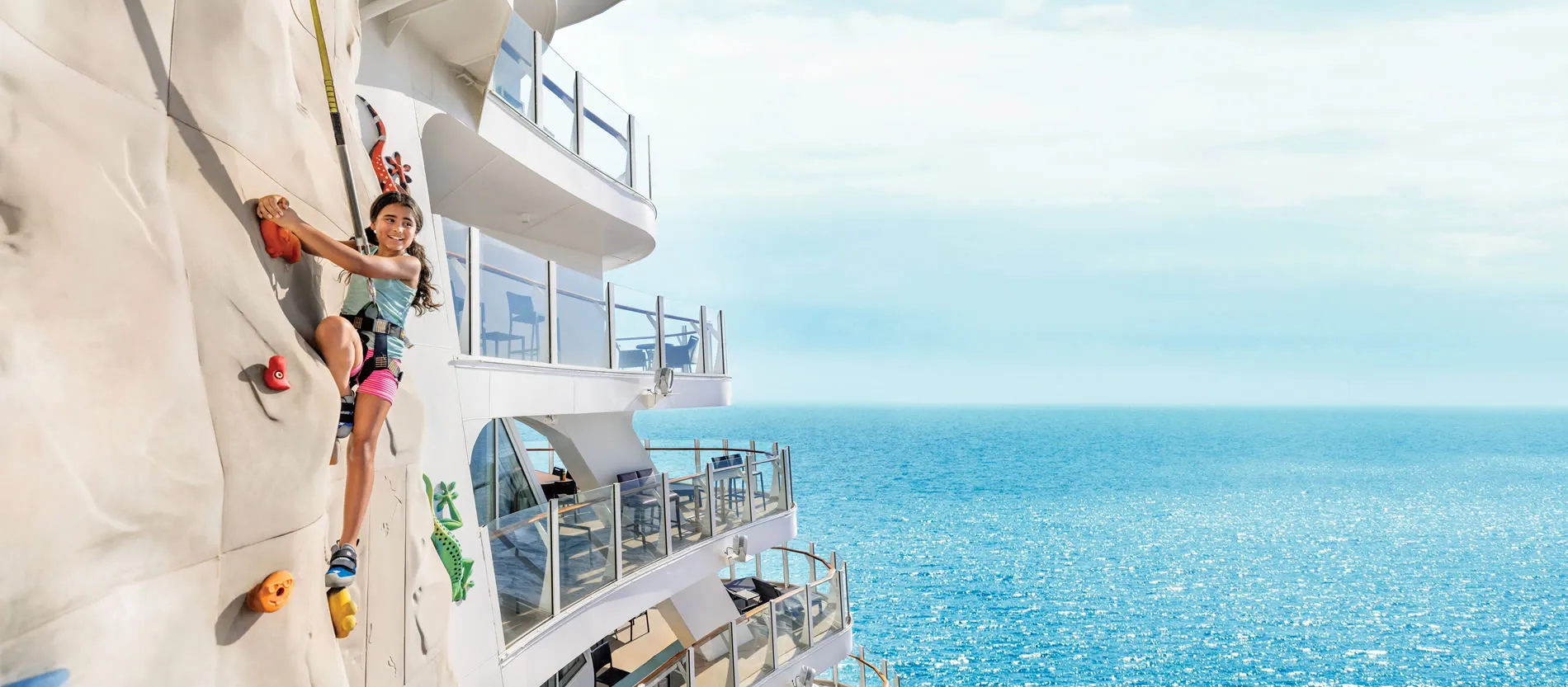 Child rock climbing on cruise ship deck with ocean view