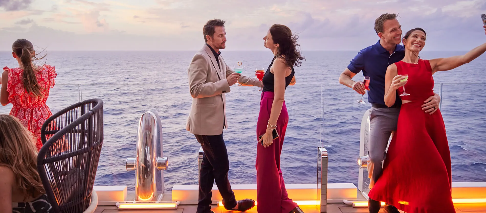 Elegant couples enjoying cocktails on a cruise ship deck at sunset