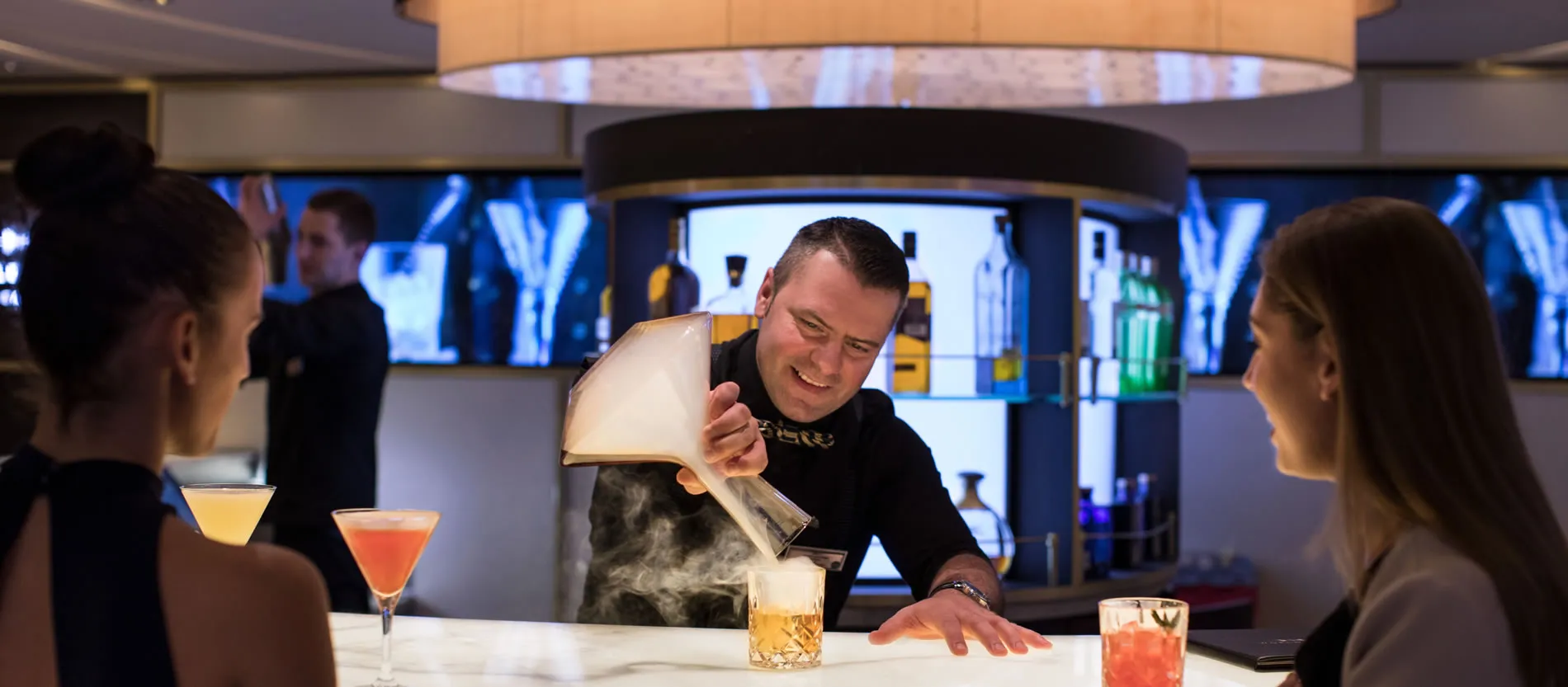 Bartender pouring smoking cocktail at modern bar with colorful drinks