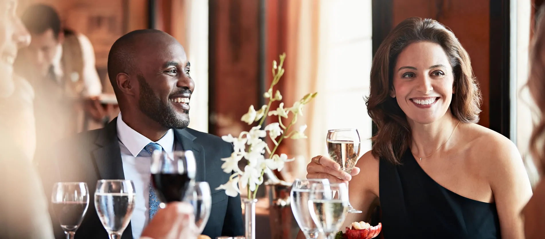 Elegantly dressed people smiling and enjoying drinks at a social gathering