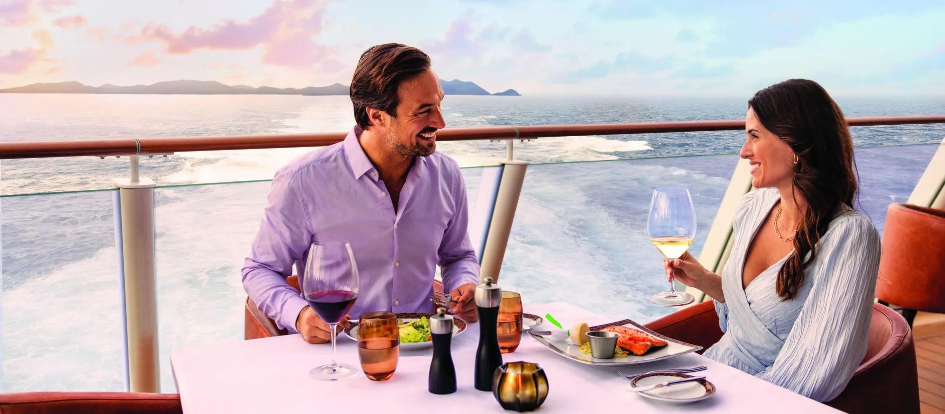 Couple enjoying wine and meal on cruise ship deck with ocean view