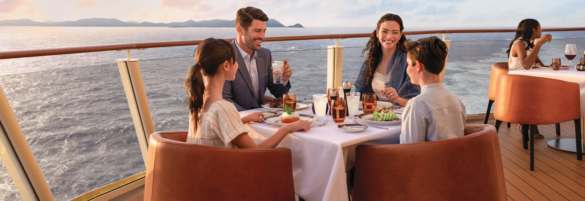 Family dining together on cruise ship deck with scenic ocean view