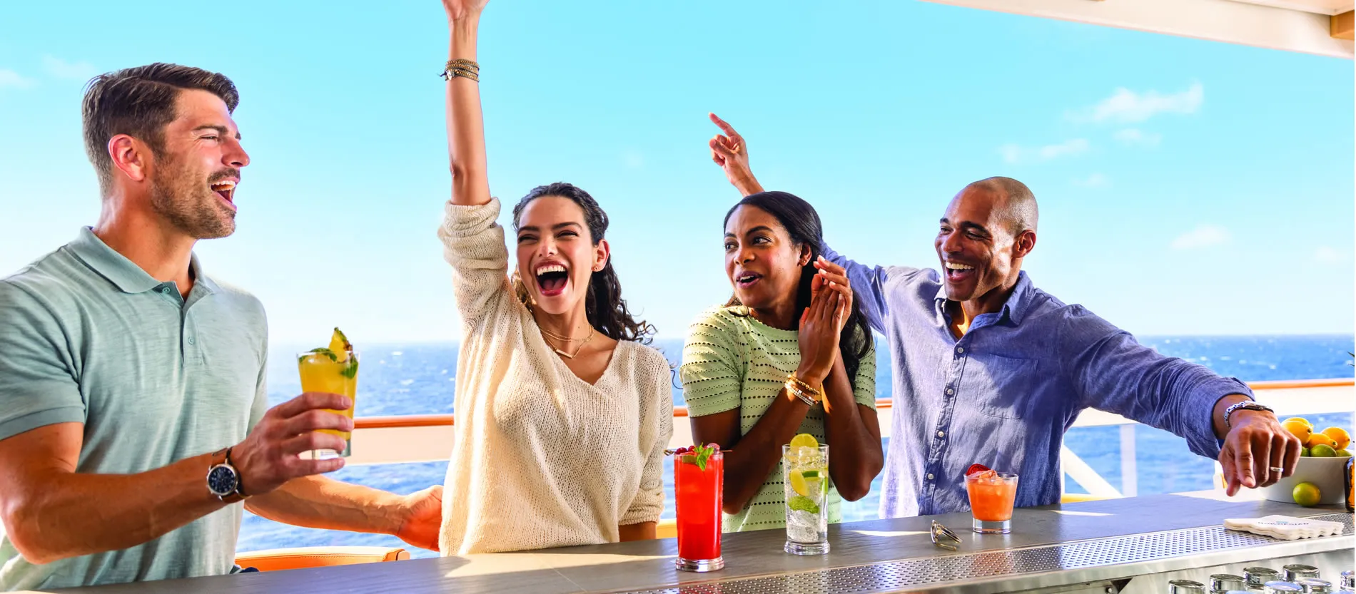 Friends enjoying cocktails and laughing together on a sunny cruise deck