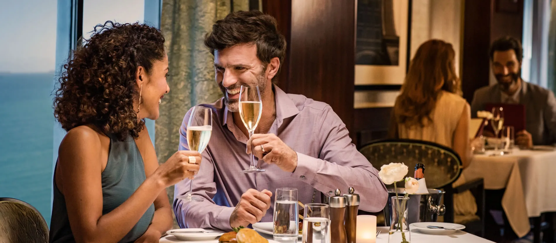 Couple enjoying champagne together at a seaside restaurant with ocean view