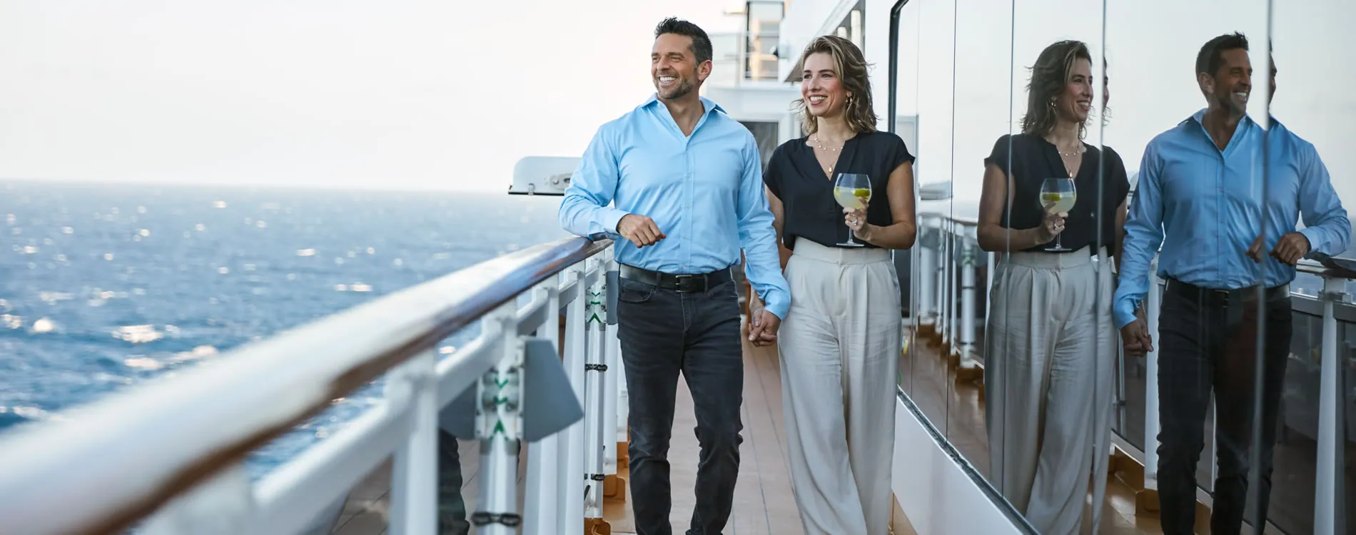 Two people enjoying wine on a cruise ship deck with ocean view