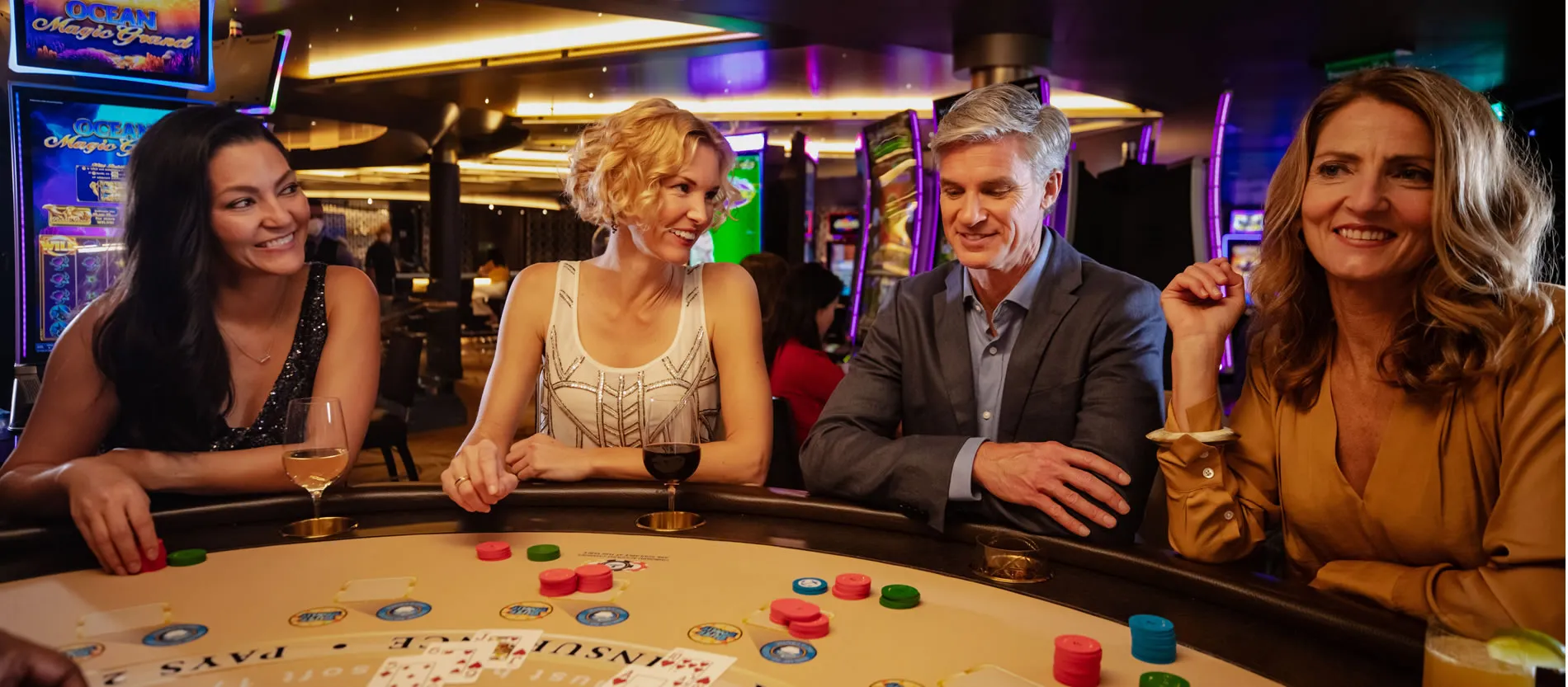 Four people enjoying drinks and playing at a casino gambling table