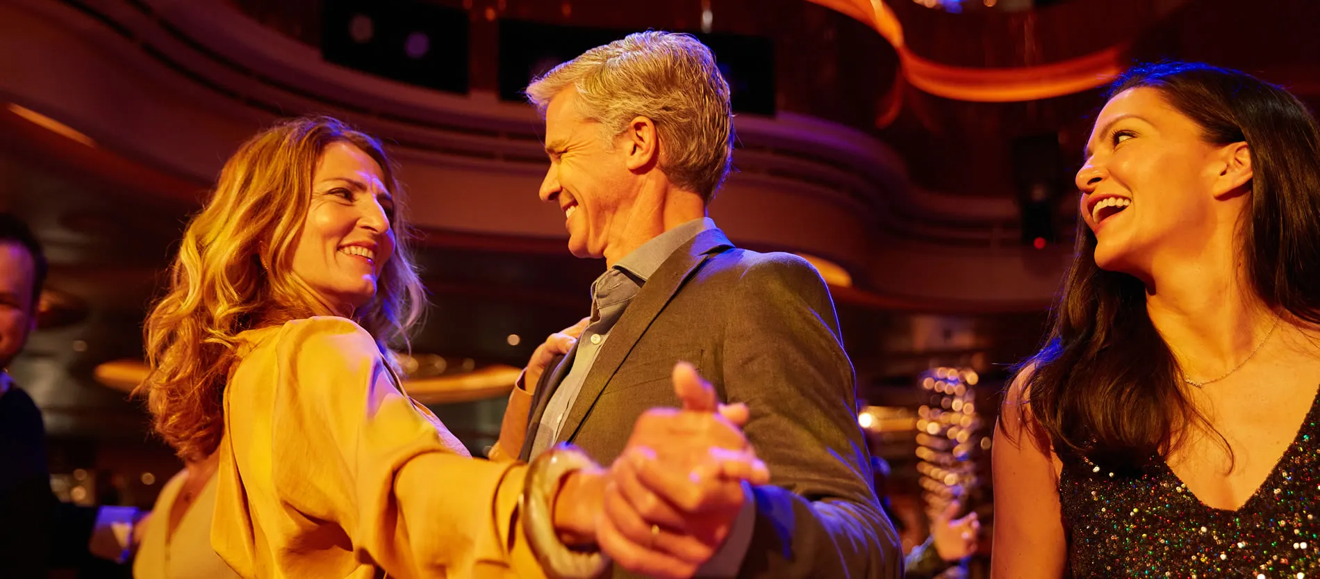 Three people laughing and enjoying themselves at a vibrant event