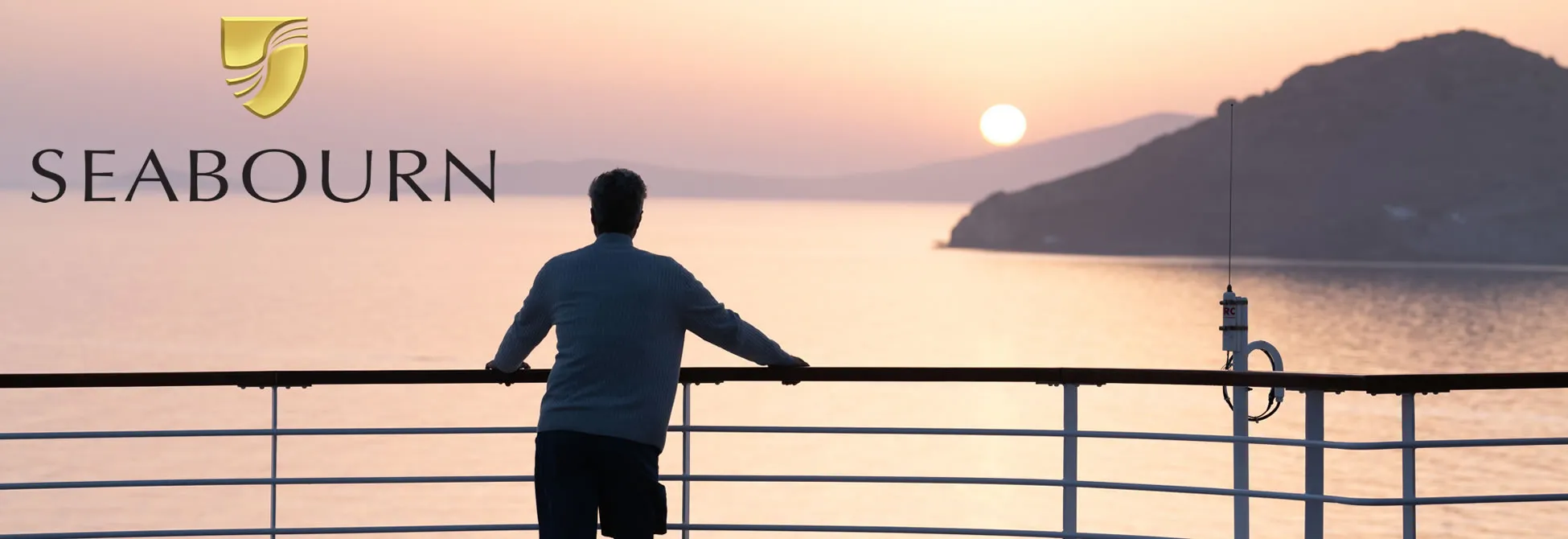 Person on cruise ship deck watching sunset over mountainous coastline