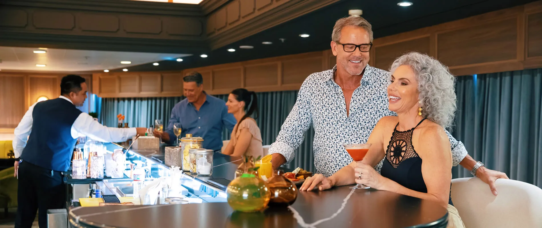 Older couple enjoying cocktails at a stylish bar with bartender