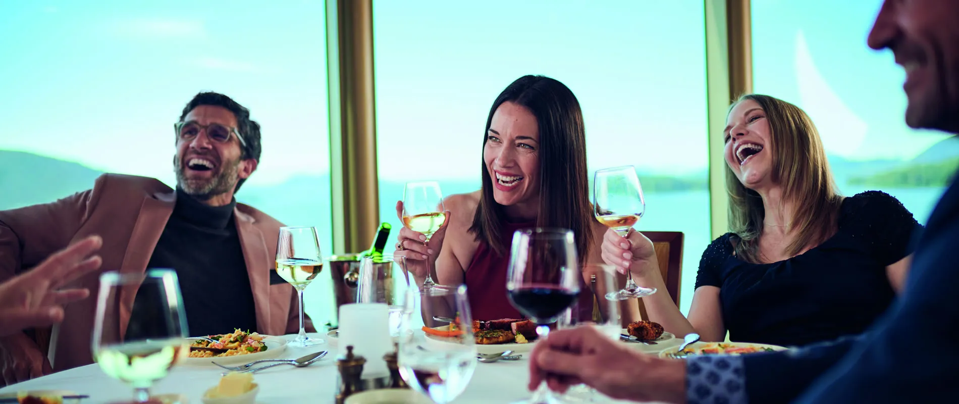 Friends laughing and enjoying wine together at a restaurant table