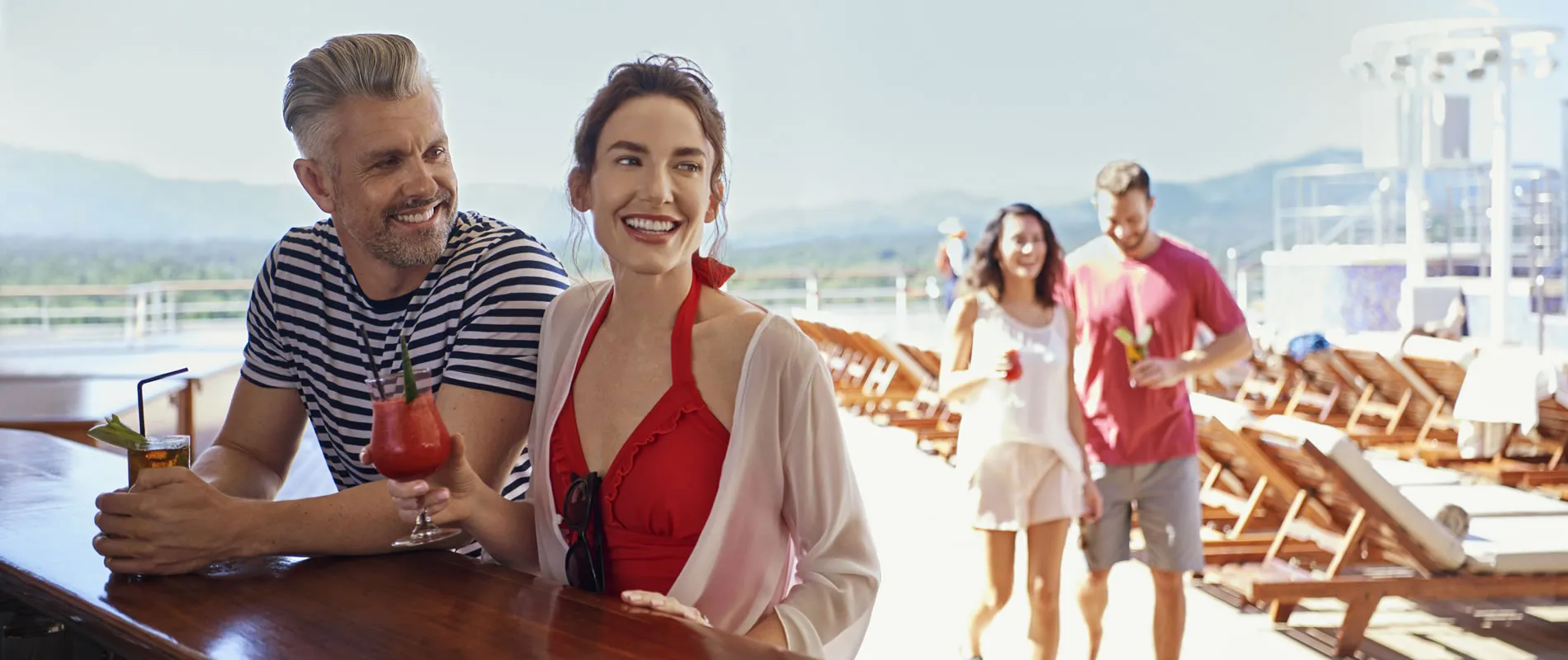 Smiling friends enjoying tropical cocktails on a cruise ship deck