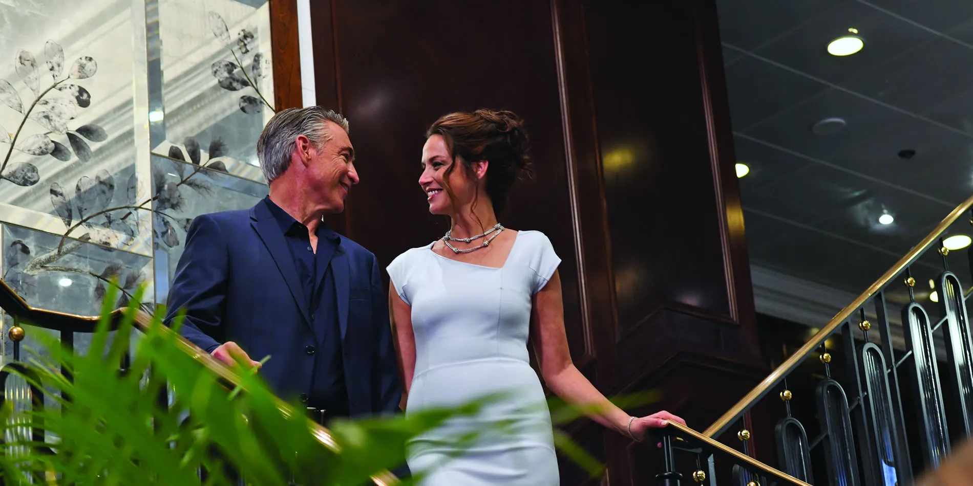 Elegantly dressed couple smiling together on an ornate staircase