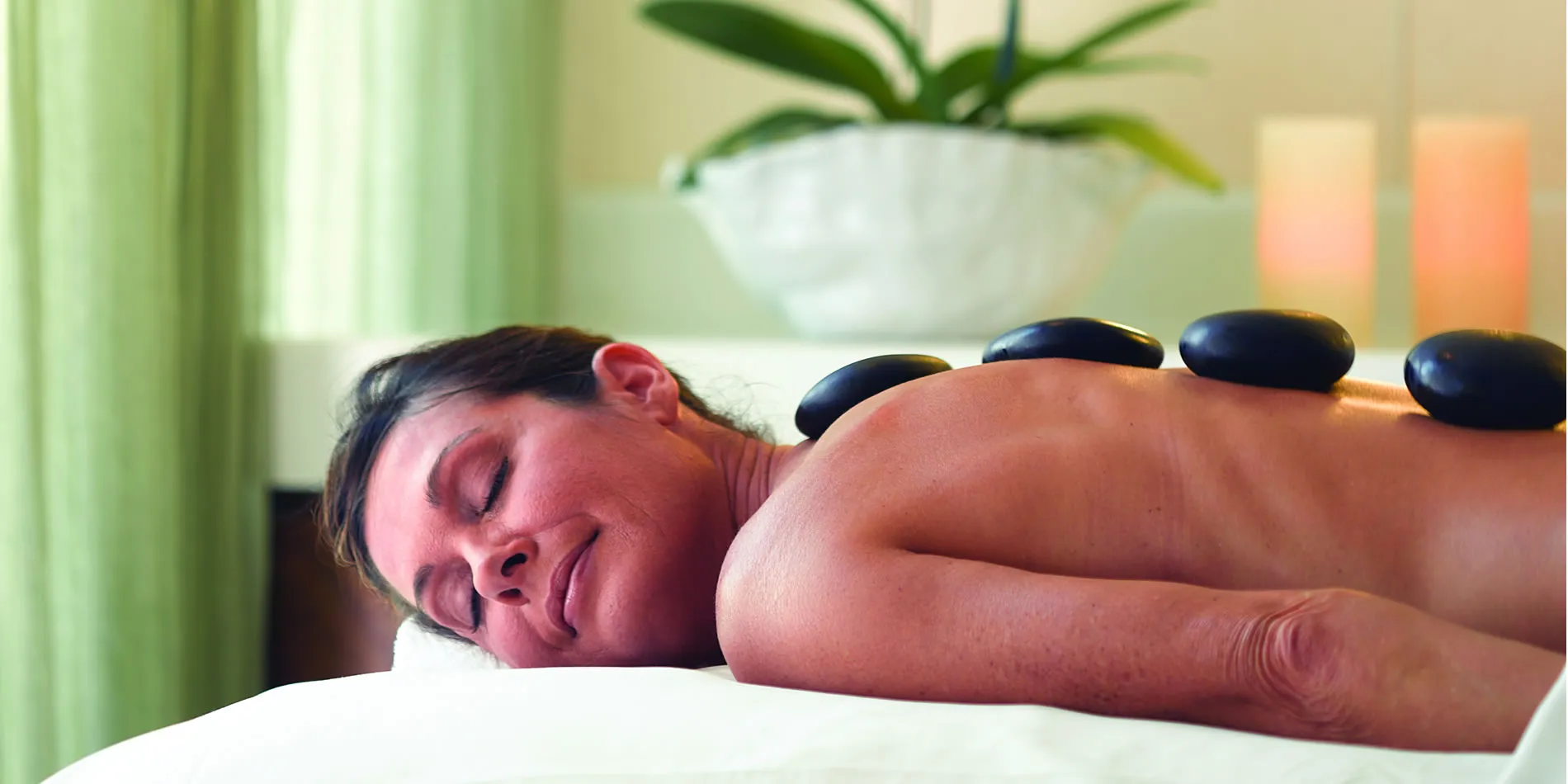 Person relaxing during hot stone massage with stones on back