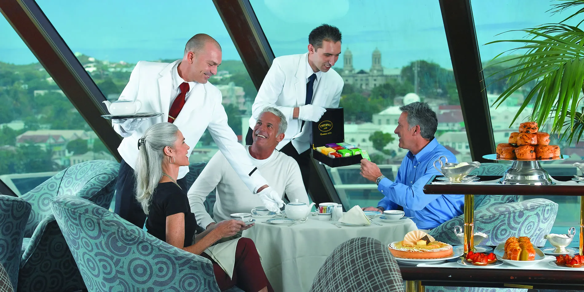 Elegant dining with waiters serving tea and pastries in scenic restaurant